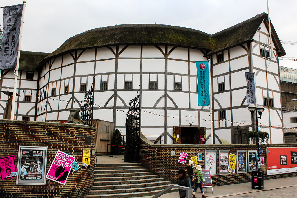 Fachada del teatro Shakespeare's Globe en Londres con banderas y carteles de eventos.