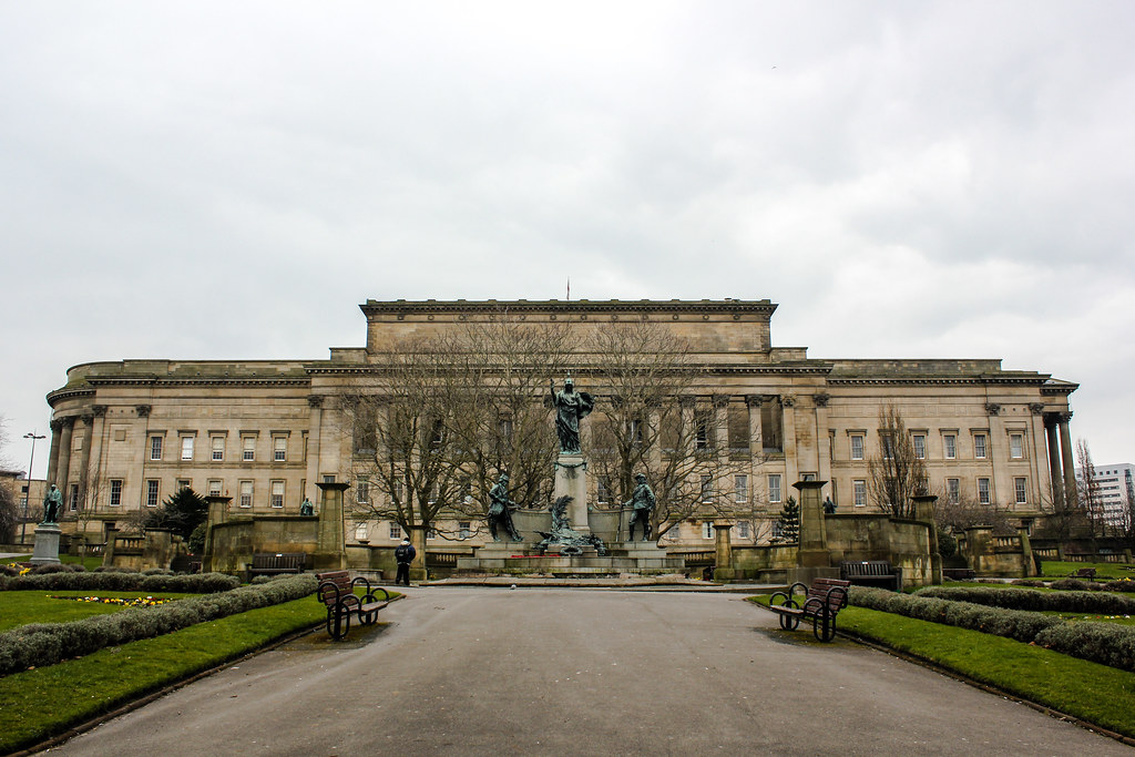 Fachada del St. George's Hall en Liverpool con estatua y jardines.