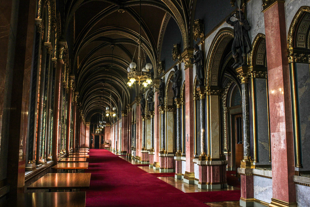 Suntuoso corredor con alfombra roja y columnas decorativas en el Parlamento de Budapest.