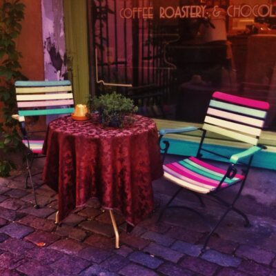 Acogedora terraza del café Kehrwieder en Tallin con sillas de colores y mesa con mantel.