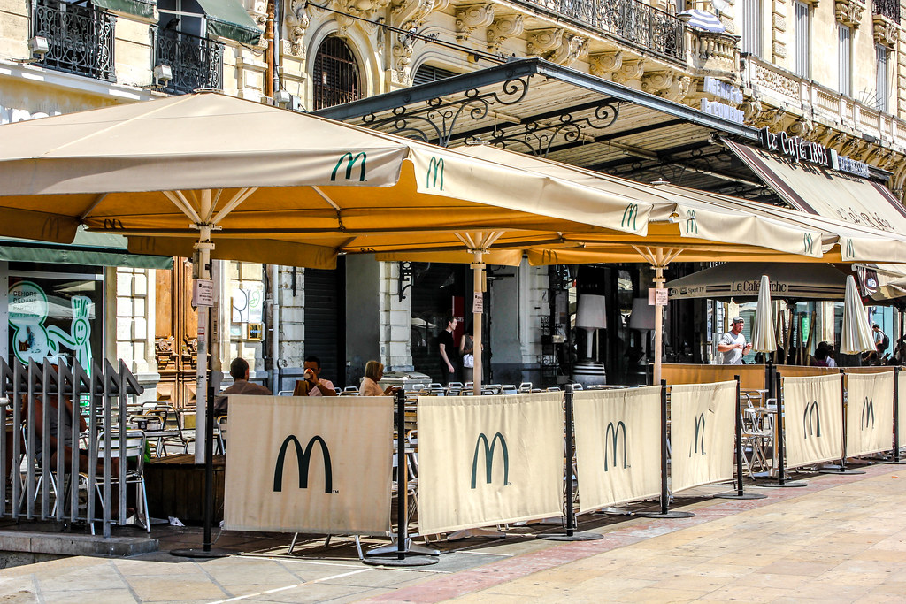 Terraza exterior de McDonald's con sombrillas en zona peatonal urbana.