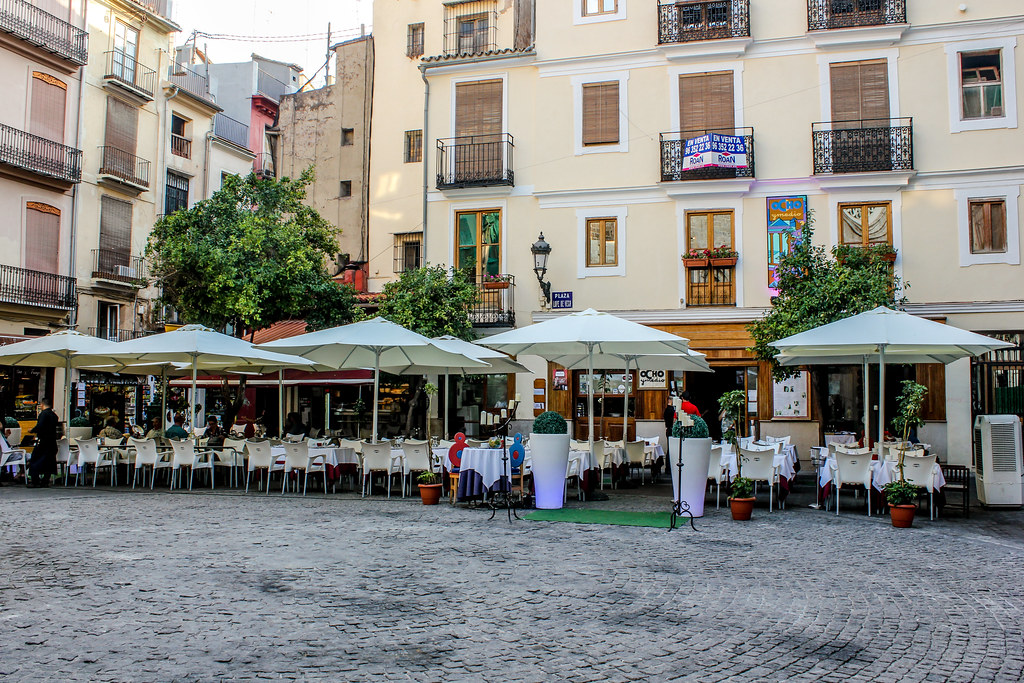 Terraza de restaurante en la plaza Lope de Vega de Valencia con mesas bajo sombrillas.
