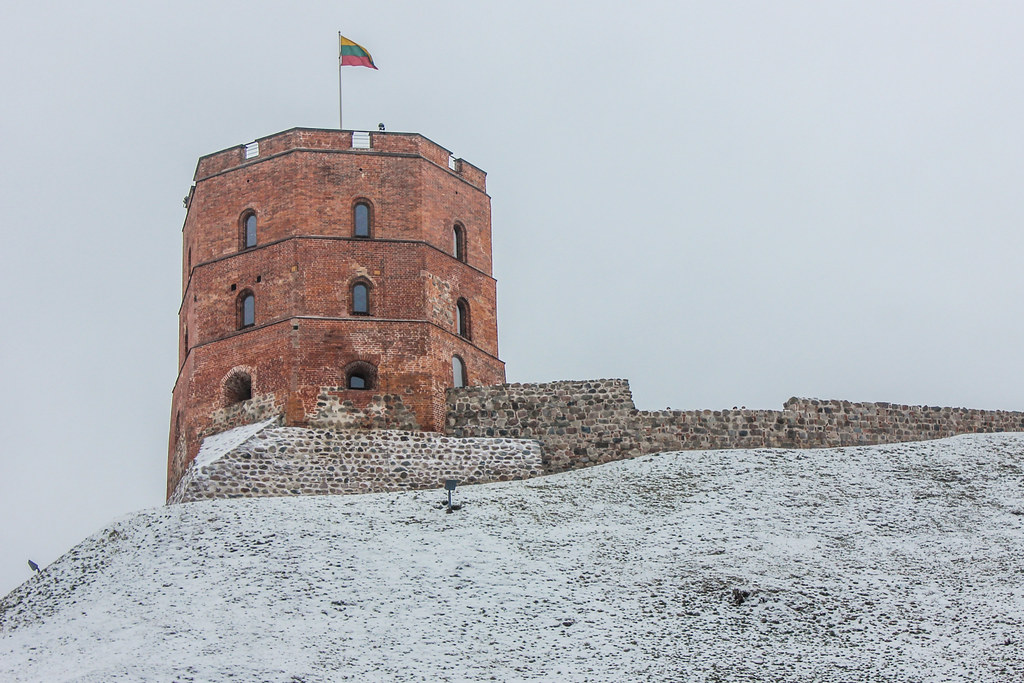 Torre de Gediminas en una colina nevada con la bandera de Lituania ondeando, en Vilna.