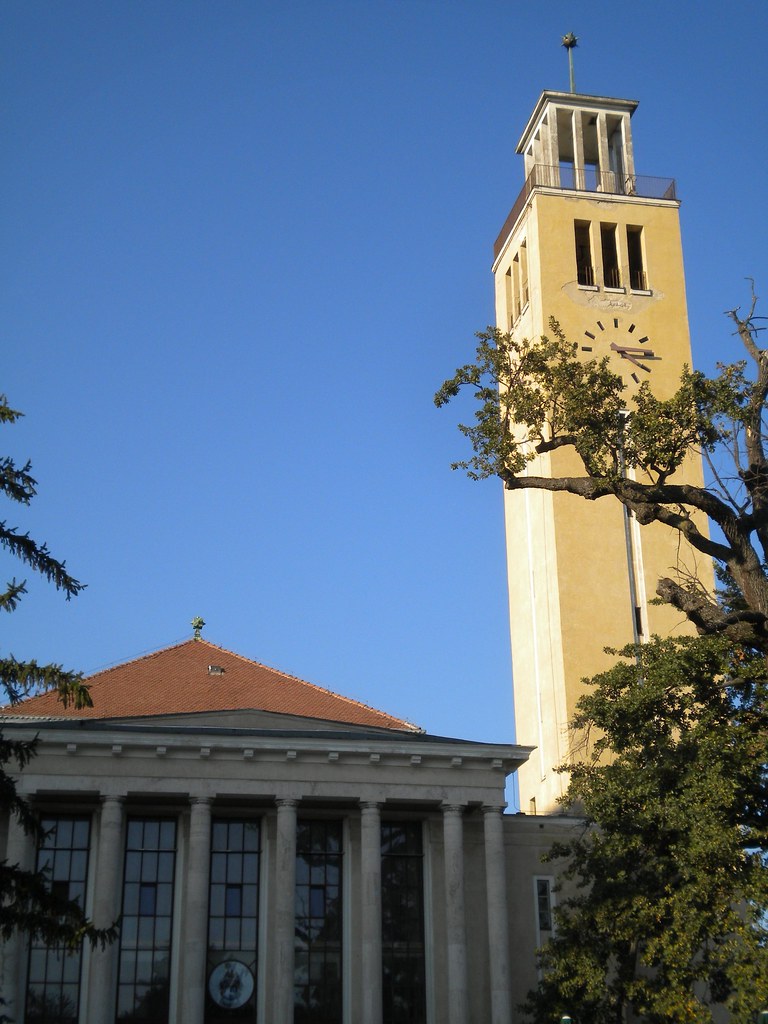 Torre del reloj de la Universidad de Debrecen bajo cielo azul claro.