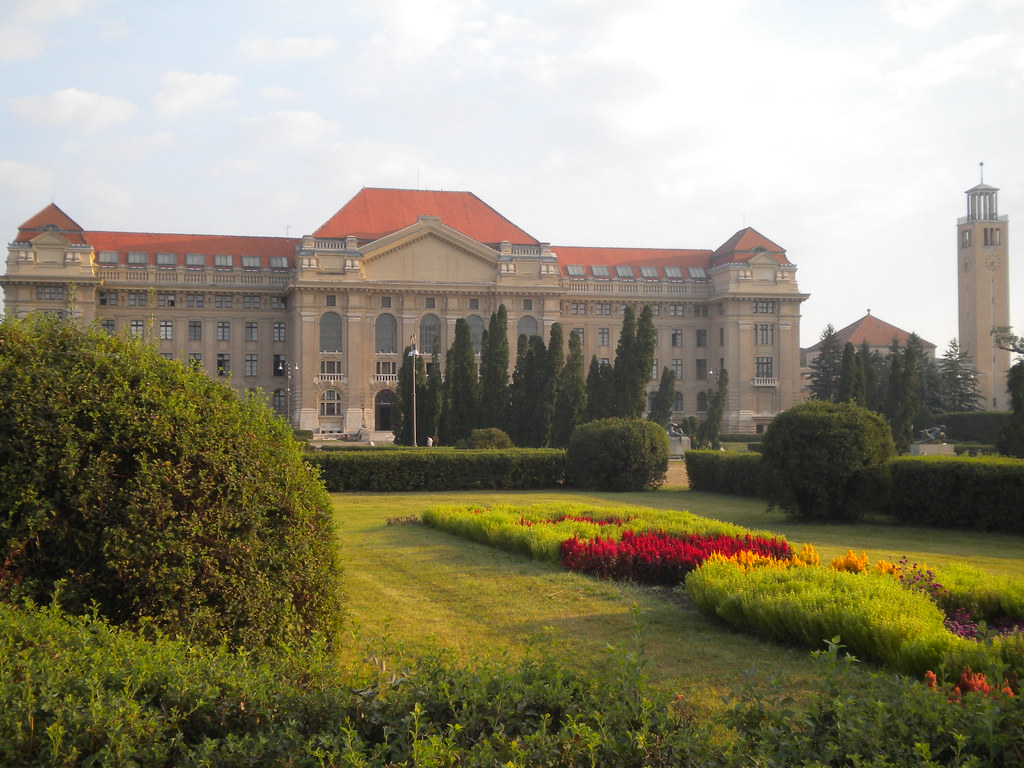 Edificio principal de la Universidad de Debrecen con jardines coloridos.