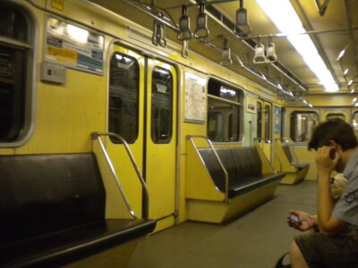 Interior del vagón de metro amarillo en Budapest con pasajero sentado.