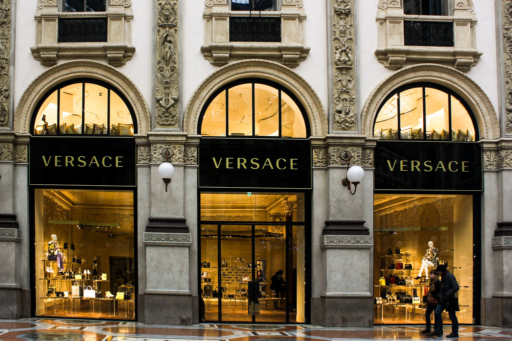 Fachada de la tienda Versace en la Galleria Vittorio Emanuele II en Milán con peatones en primer plano.