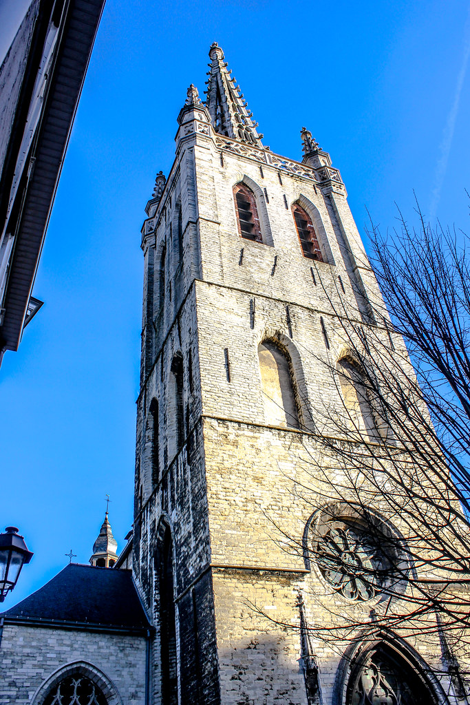 Vista ascendente de la torre de la iglesia gótica con cielo azul en el fondo.