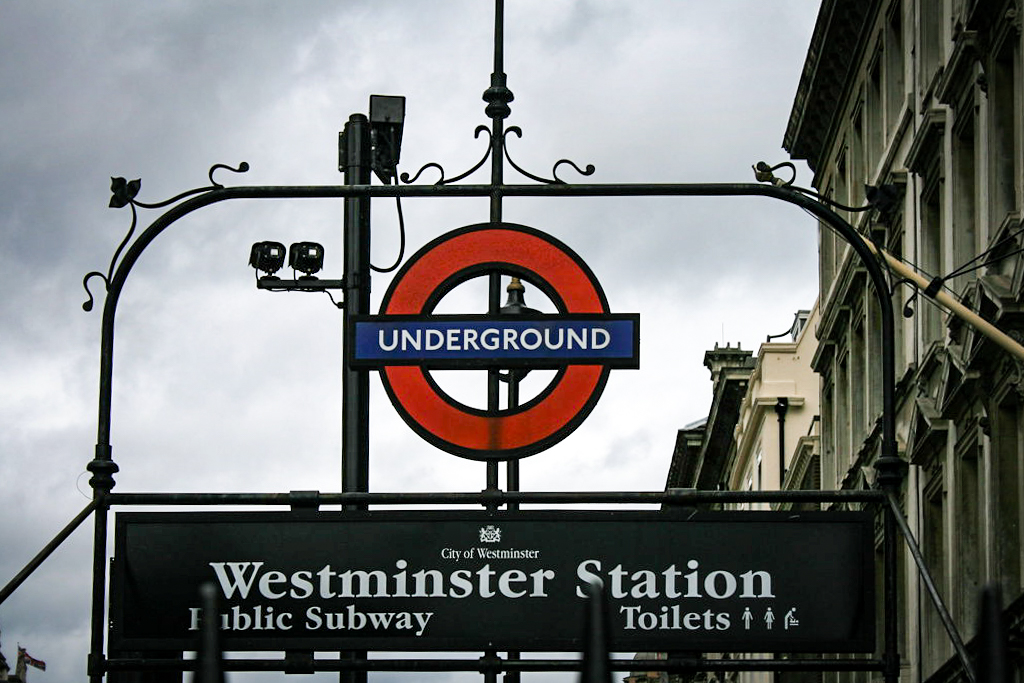 Señalización clásica del metro de Londres con el logotipo 'Underground' sobre un cartel que indica 'Westminster Station'.